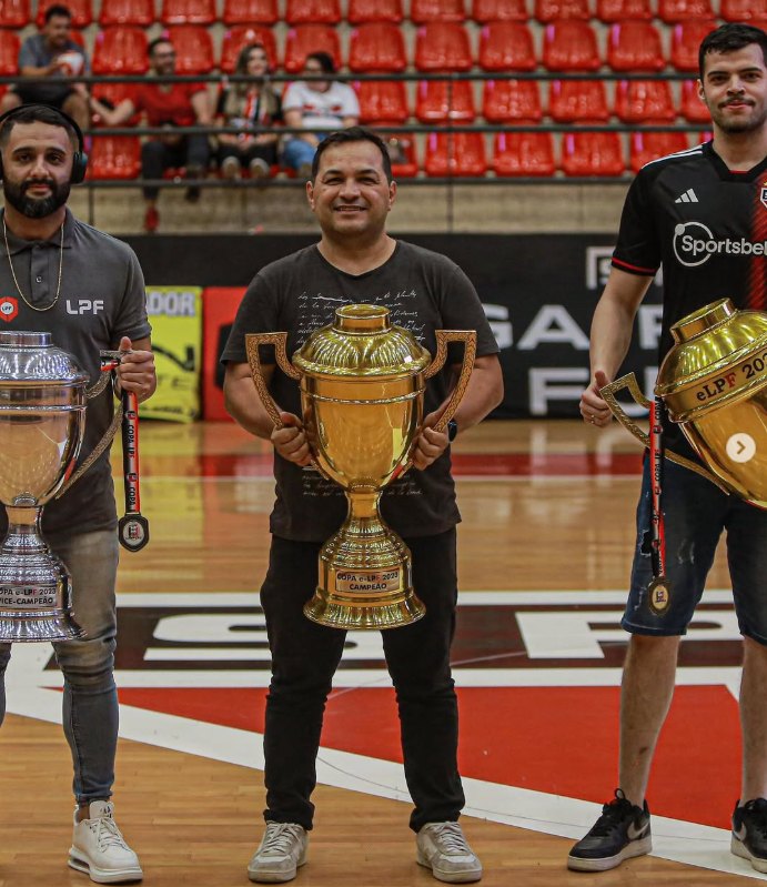 Jura na quadra segurando o troféu de campeão, ao lado de atletas premiados